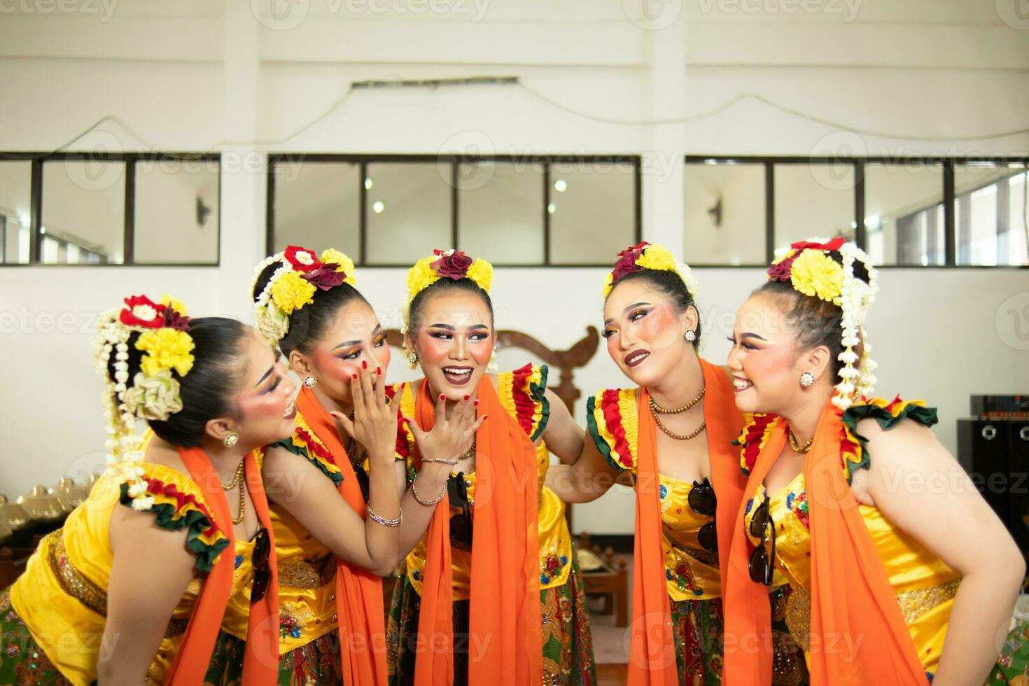 a group of traditional Javanese dancers laughing together with ridiculous faces and full of joy while on stage photo