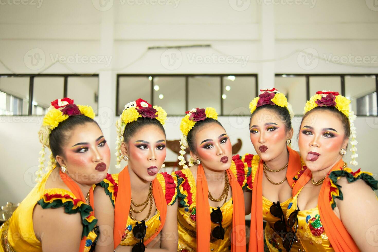 a group of traditional Javanese dancers laughing together with ridiculous faces and full of joy while on stage photo