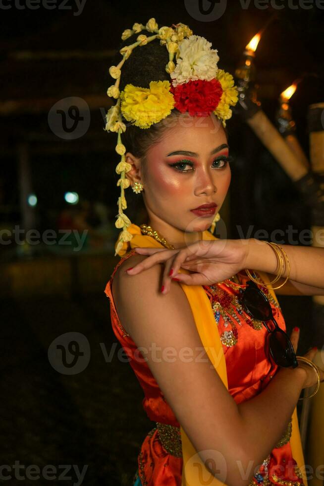 a Javanese dancer poses with sharp eyes and a golden costume on stage photo