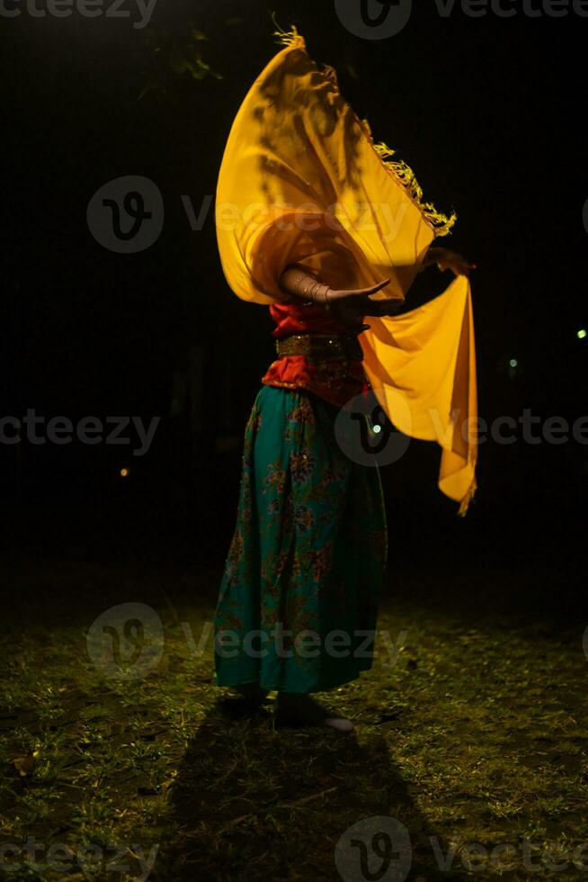 un tradicional indonesio bailarín bailes con un amarillo bufanda ese flotadores en el aire foto