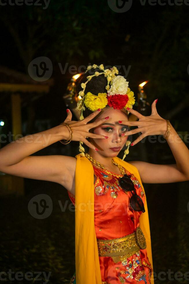 a Javanese dancer poses with sharp eyes and a golden costume on stage photo