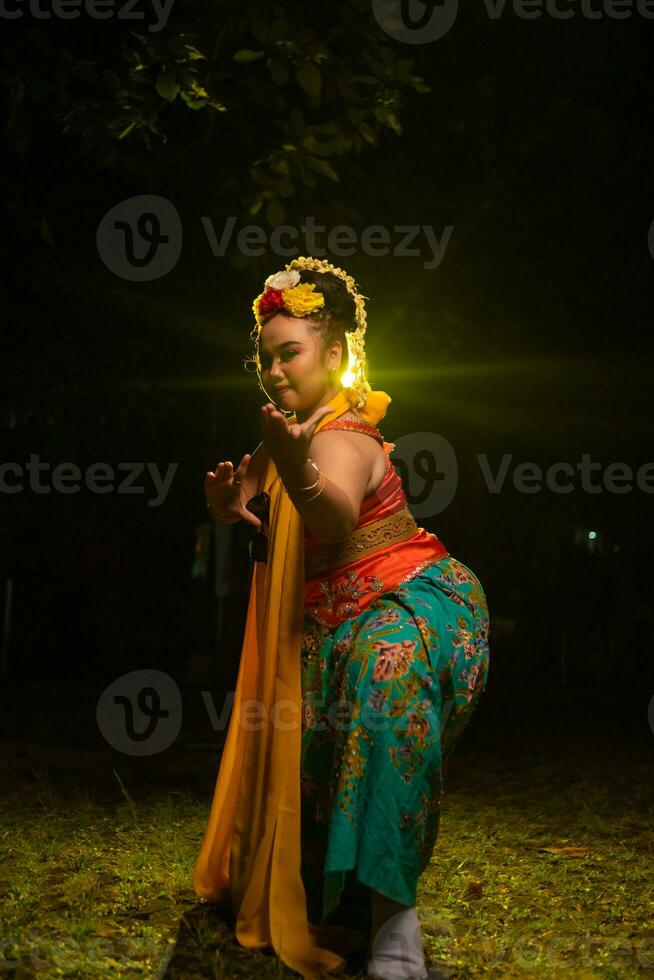 retrato de un indonesio bailarín con un oro cinturón bailando graciosamente foto