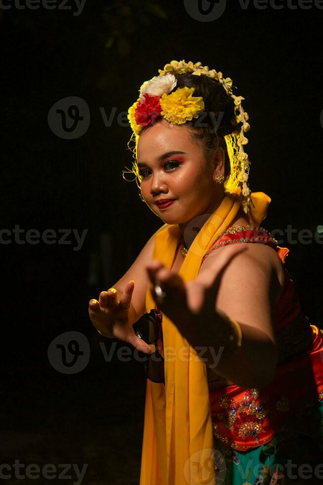 retrato de un indonesio bailarín con un oro cinturón bailando graciosamente foto