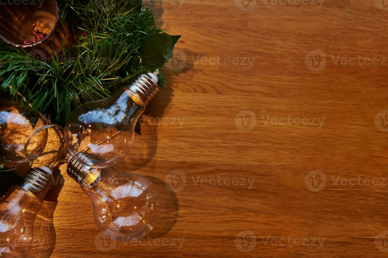 Flat lay composition with ornament of transparent lamps on a pine branch lying on a wooden board with copy space photo