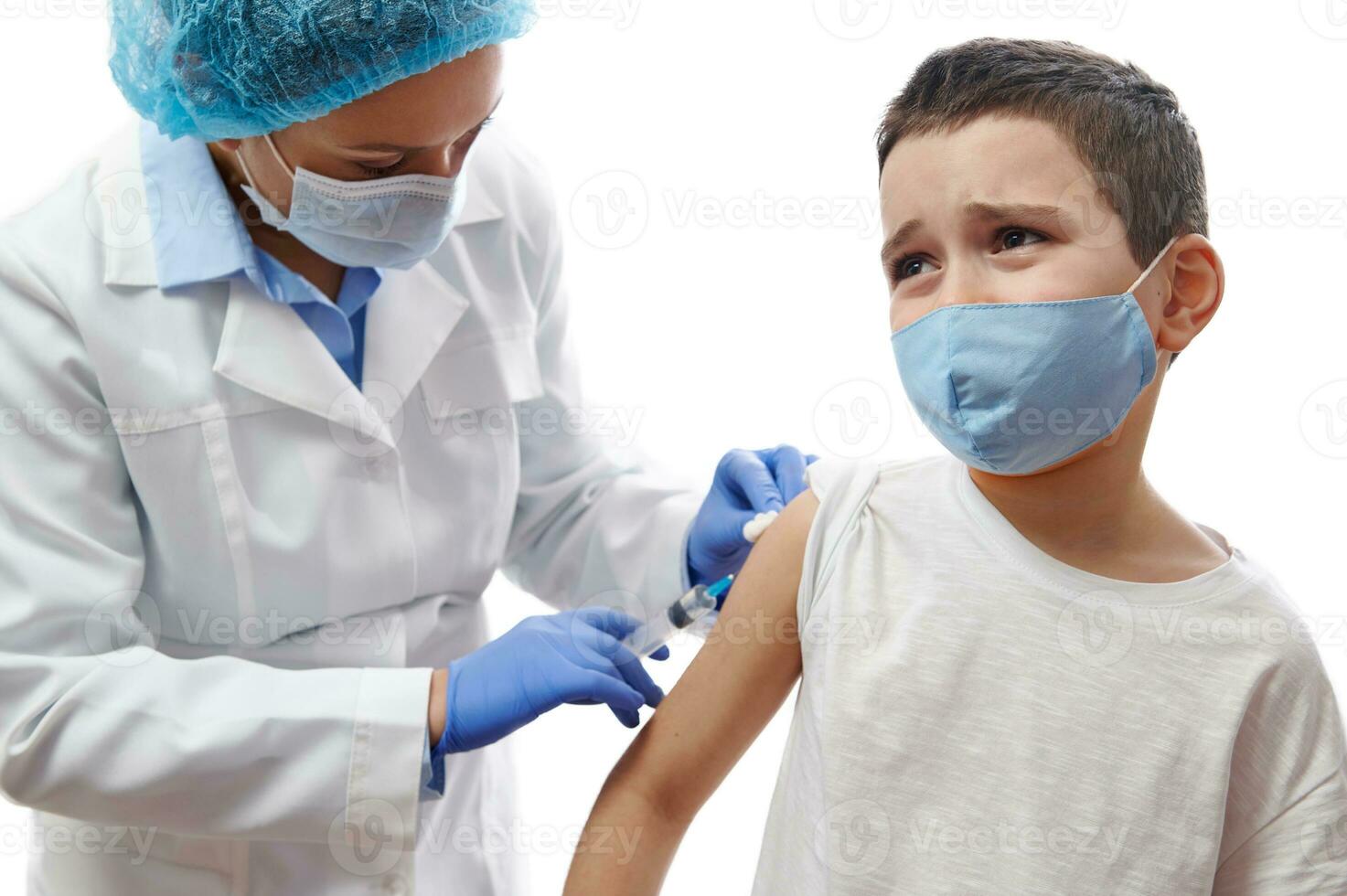 Doctor making injection on boy's hand. Vaccination on white background. Boy afraid of vaccination and injection. photo