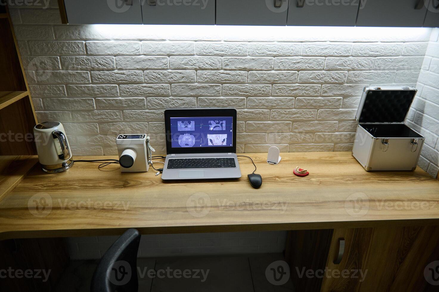 Laptop with dental X-ray on monitor screen, portable dental x-ray machine to create panoramic x-rays and dental impression of the jaw on a wooden table in the dentist's office. Dentistry photo