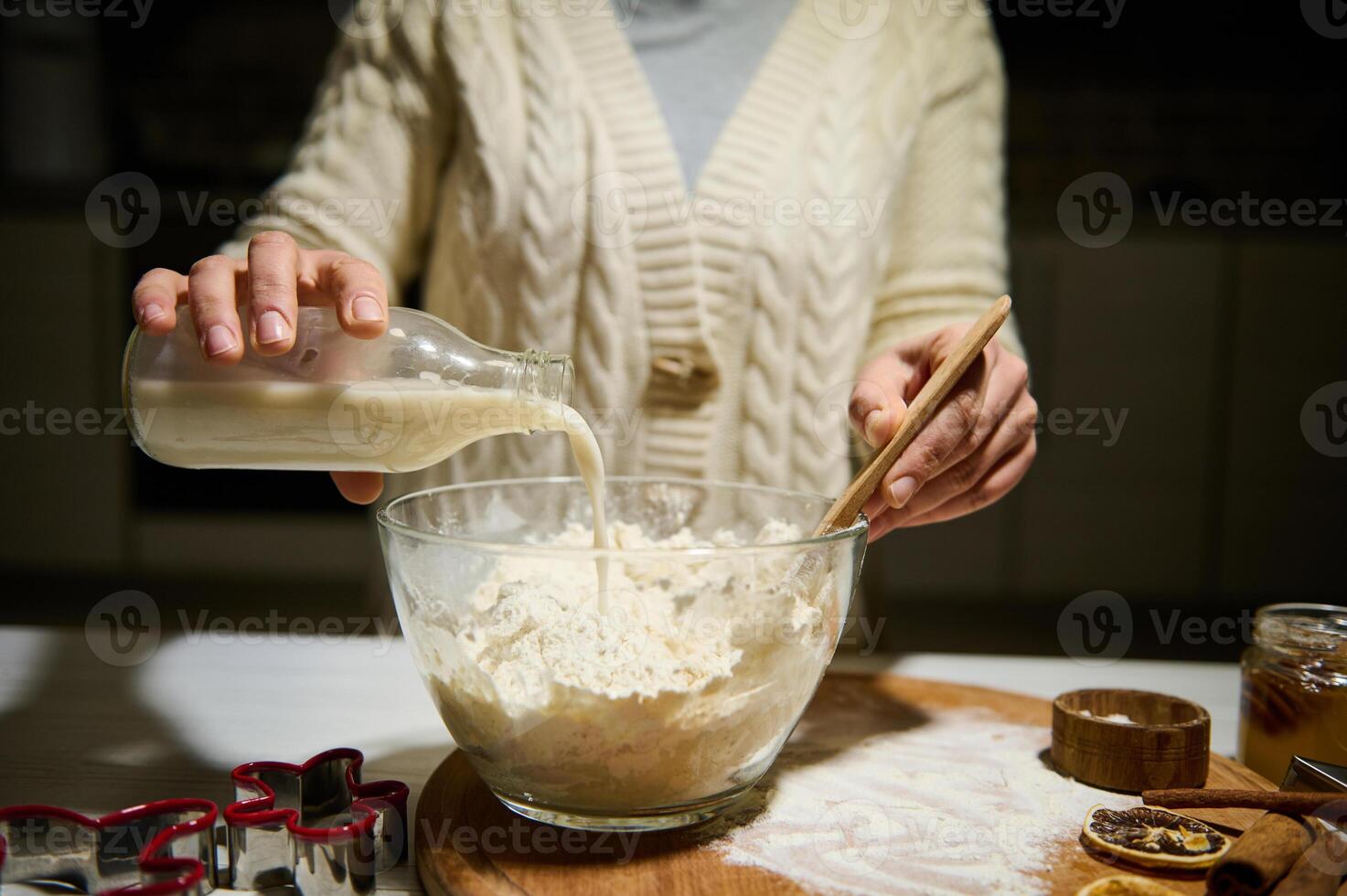 Premium Photo  Close-up cooking process. women's hands hold plate of flour  in her hands and add it with spoon to bowl with ingredients. on the table  cookie molds and baking molds.