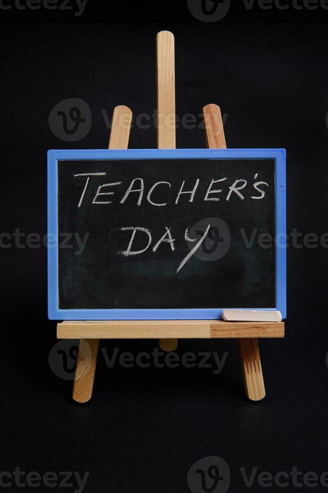 de cerca de un tiza tablero en un de madera mesa caballete con letras del maestro día , aislado en negro antecedentes con Copiar espacio. foto
