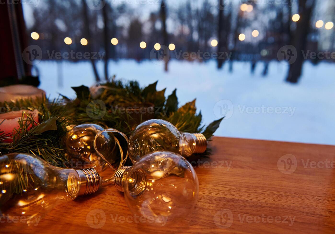 Christmas decorations. Ornament on a pine branch with candles and lamps with lights on a snow covered background. View from the window. photo