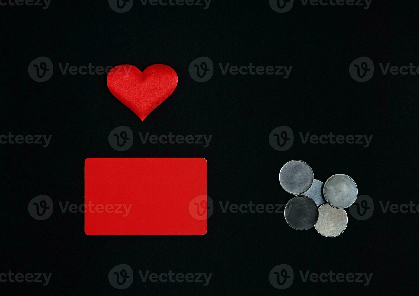 A horizontal red rectangle, red heart and money coins on a black background. Border, copy space, top view, celebration, holiday photo