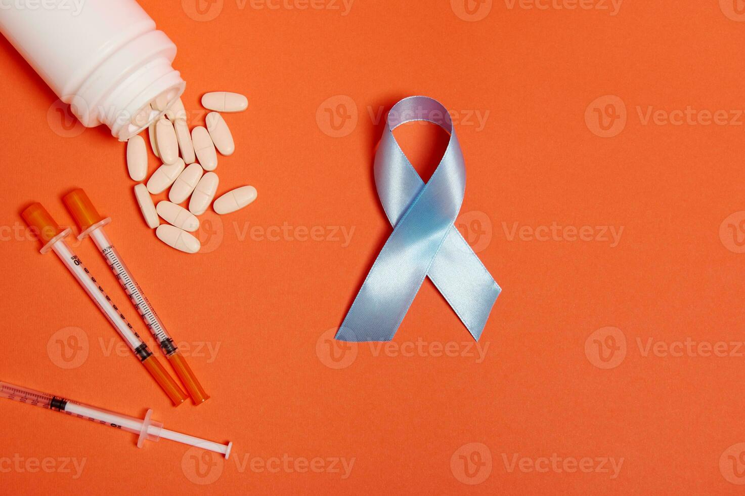 World diabetes day awareness concept. Flat lay of insulin syringes, pharmaceutical pills scattered from white medicament container and blue ribbon, symbol of World Diabetes Awareness Day 14 November. photo