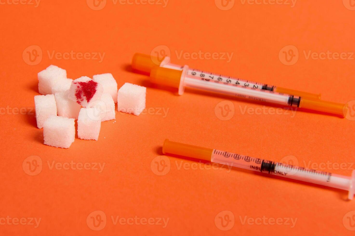 Refined pure white sugar cubes with blood drop and insulin syringes lying on orange background with copy space for World Diabetes Day medical advertisement. World diabetes awareness day, 14 November photo