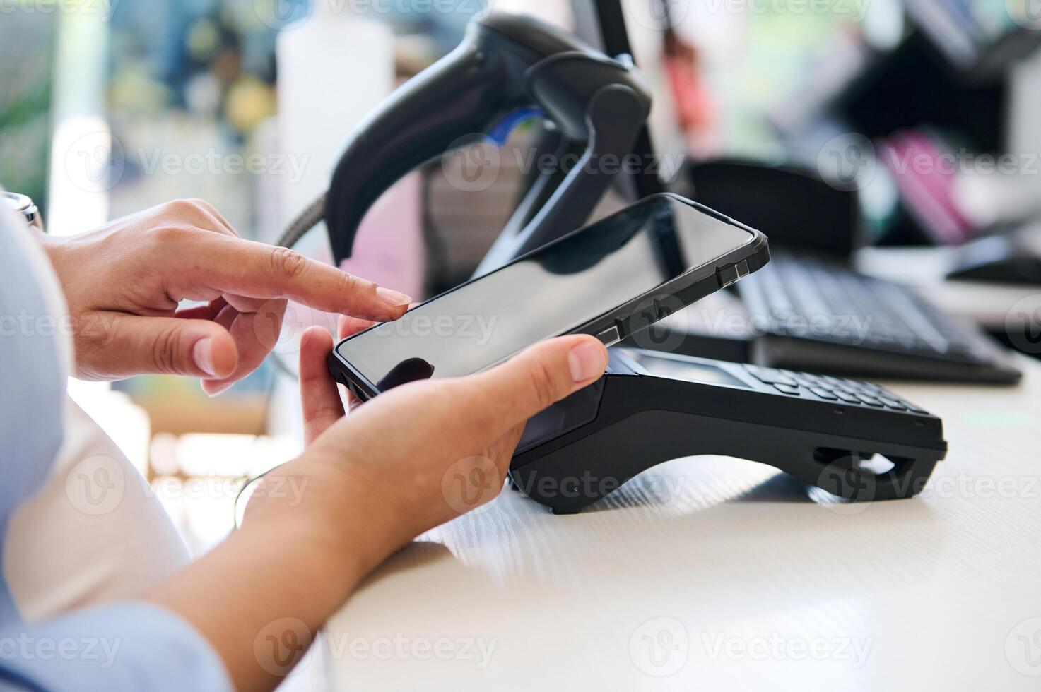 Close-up hand holding smartphone over credit card reader, making contactless payment via NFC and mobile internet banking photo