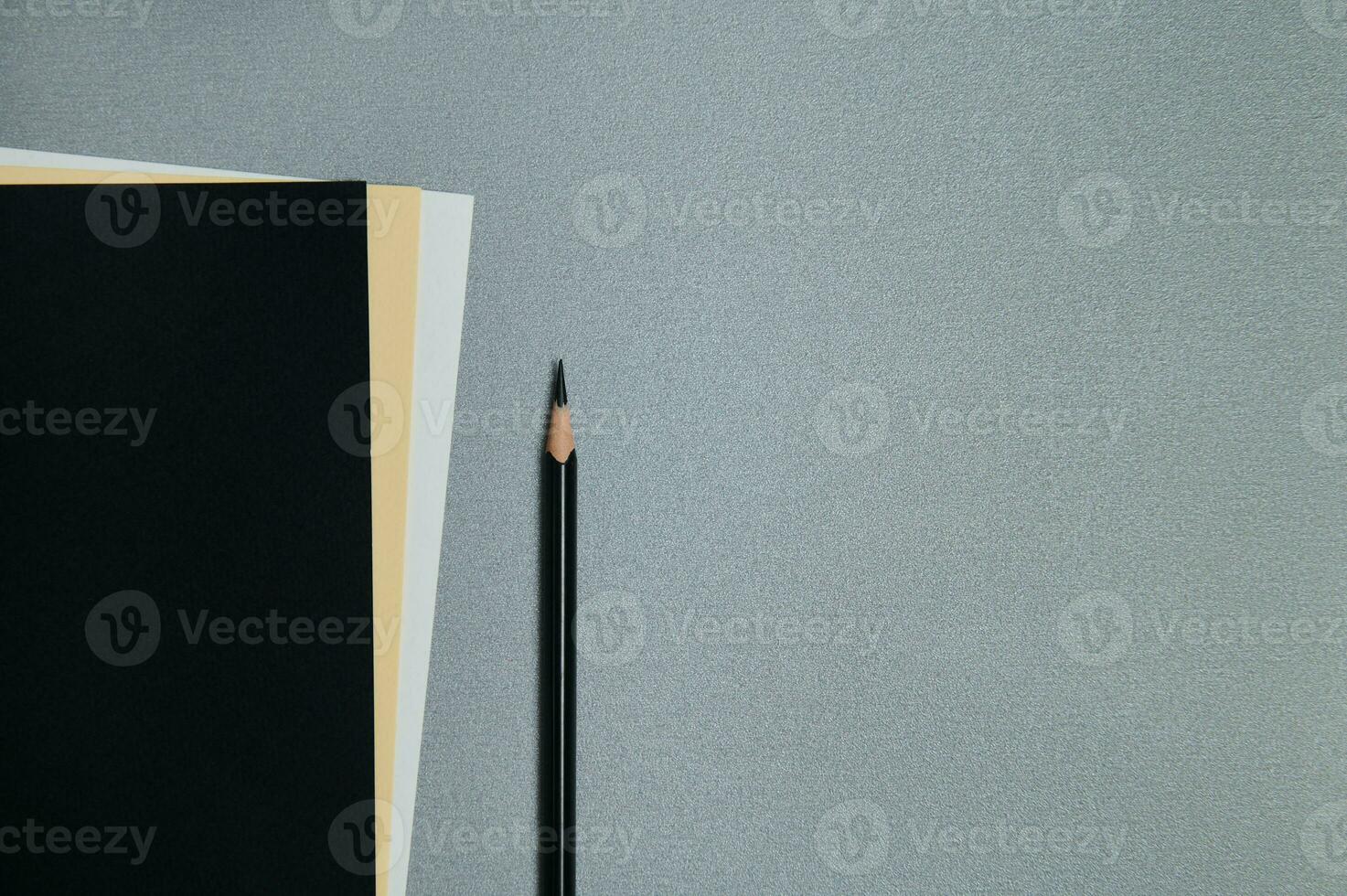 Black, yellow and white sheets of paper and a black pencil on a gray background. Flat lay, copy space, top view photo