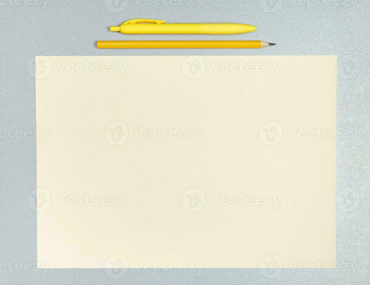 plano laico composición de amarillo bolígrafo, lápiz y sábana de papel en un gris superficie foto