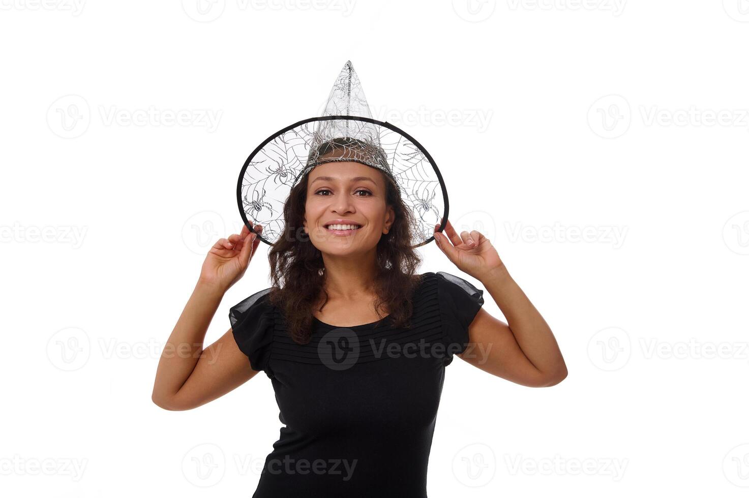 Isolated portrait on white background with copy space for Halloween advertisement of an attractive young woman smiling with beautiful toothy smile, wearing a witch wizard hat and looking at camera photo