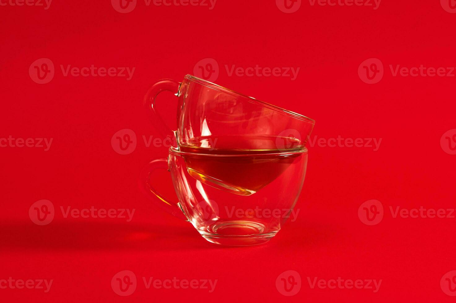 Stack of two transparent glass cups for hot drinks on a red background with copy space. photo