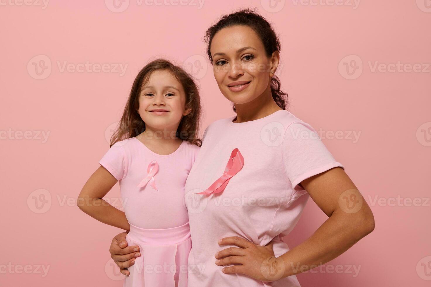 Gorgeous women of two generations, African American lady and European baby girl, in pink clothes and a ribbon, support cancer survivors. Medical Concept October 1. World Breast Cancer Awareness Day photo