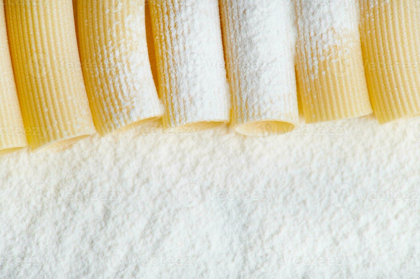 Close-up. Cropped view of neatly arranged whole wheat Italian pasta in a row on the corner of a floured surface with copy space for advertisement. Top view photo