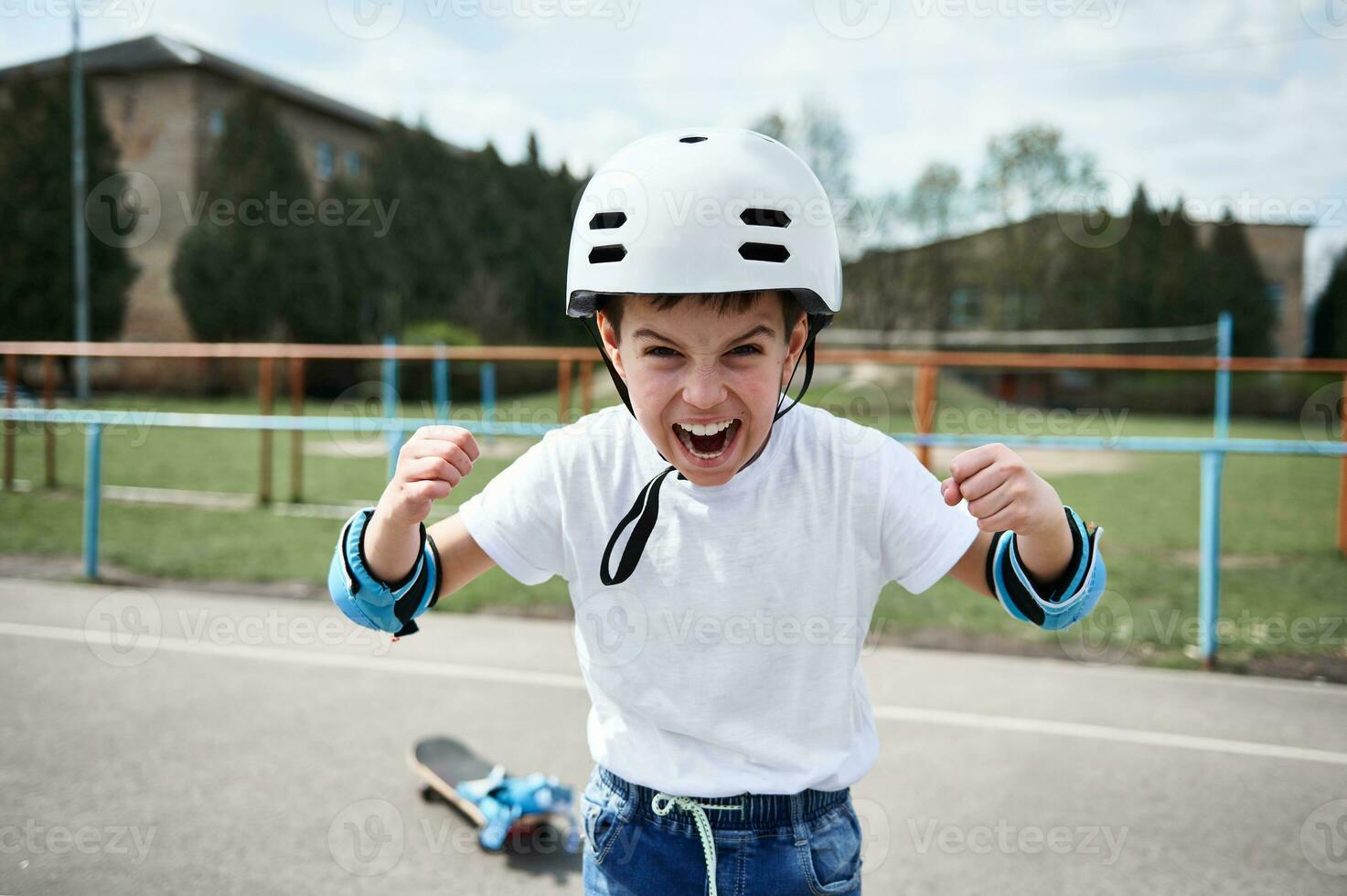 chico skater en la seguridad casco gritando y demostración puños mirando a cámara foto