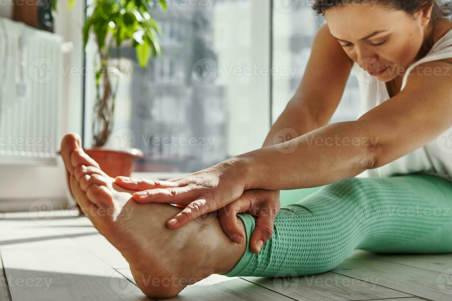 Closeup of mindful African woman stretching her body while practicing Yoga at home photo