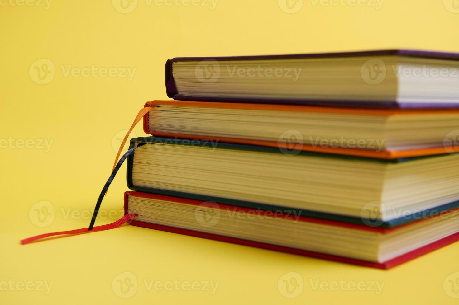 Close-up studio shot of a stack of multicolored books on yellow surface background with copy space for text. Teacher's Day concept, Knowledge, literature ,reading, erudition photo