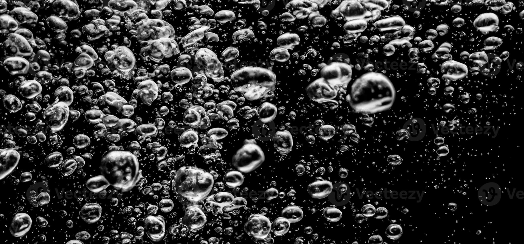 Soda water bubbles splashing underwater against black background. photo