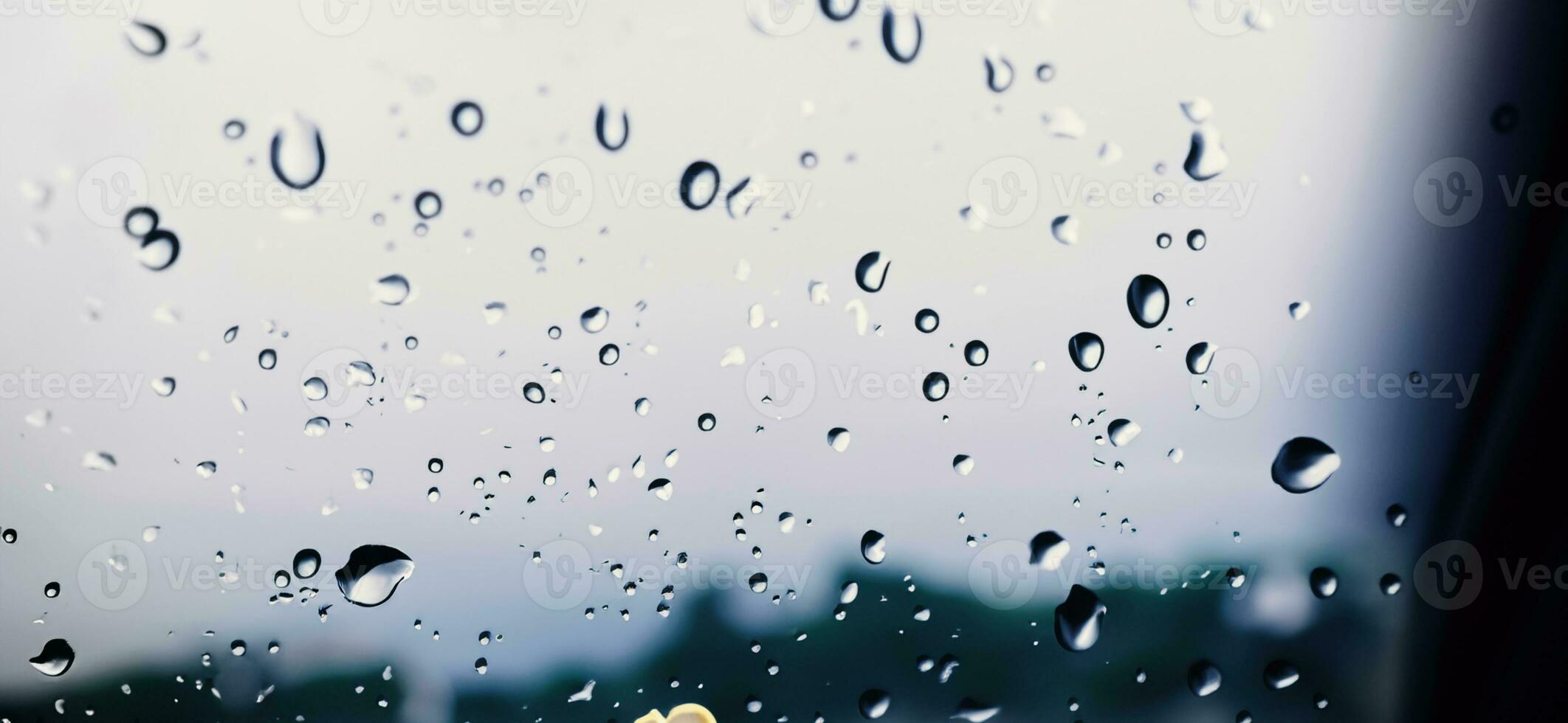 Rain shower on car windshield or car window and blurry road in background. photo