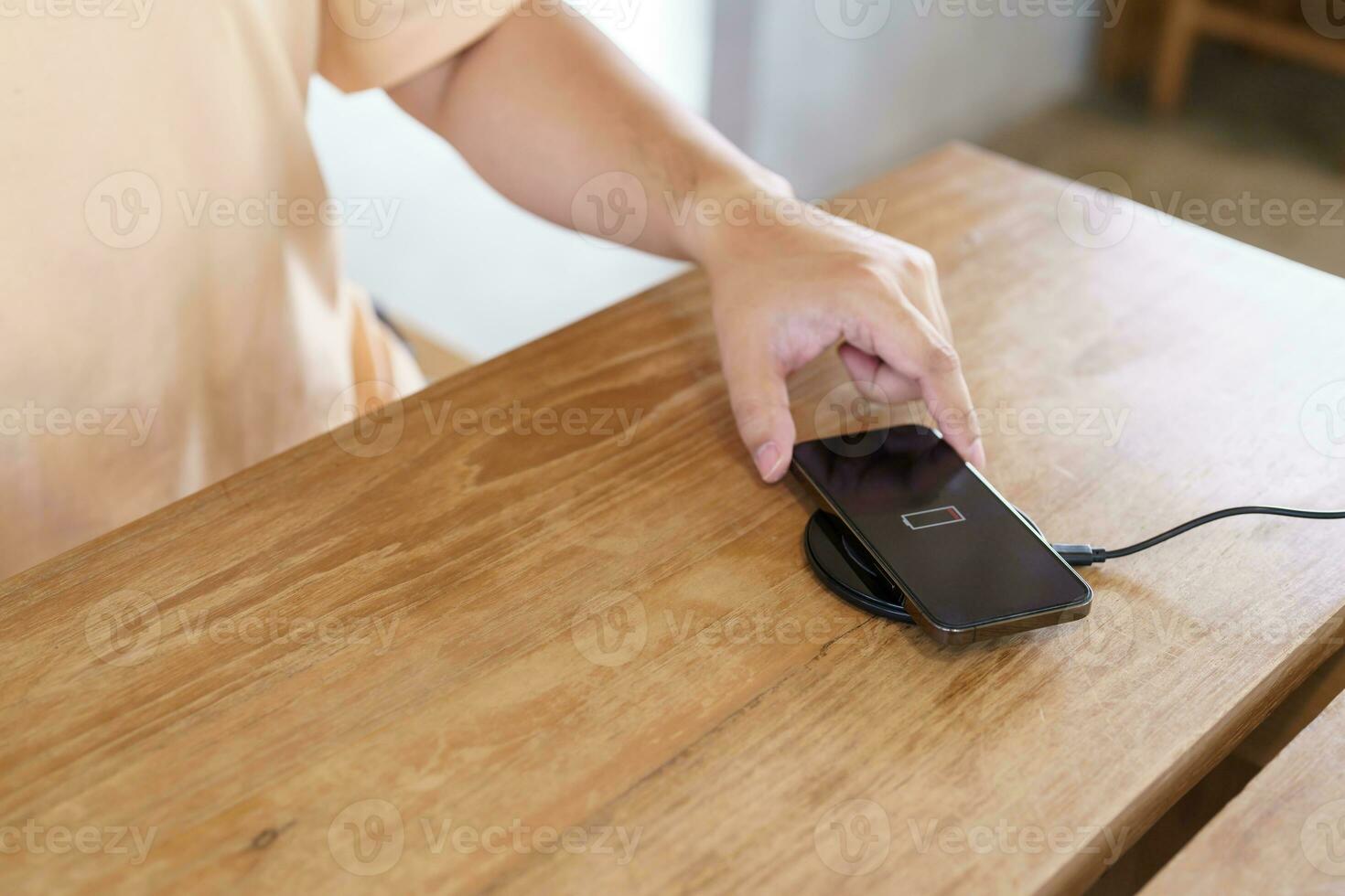 Charging mobile phone battery with wireless charging device in the table. Smartphone charging on a charging pad. Mobile phone near wireless charger Modern lifestyle technology concept. photo