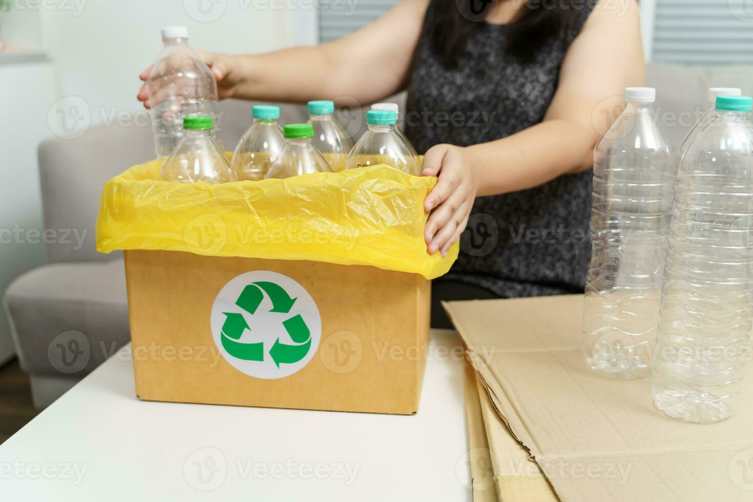 Home recycle eco green zero concept Woman throwing empty plastic bottle in recycling bin with yellow garbage bags at home. photo