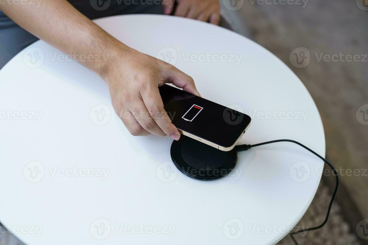 Charging mobile phone battery with wireless charging device in the table. Smartphone charging on a charging pad. Mobile phone near wireless charger Modern lifestyle technology concept. photo