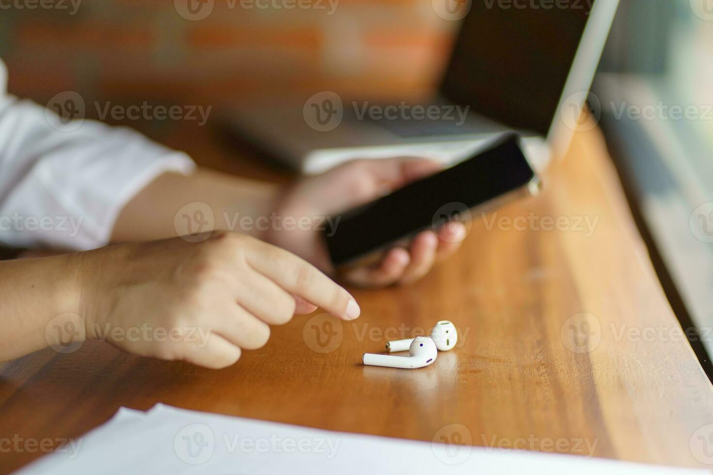 woman takes out wireless bluetooth headphones. earphones using smartphone photo