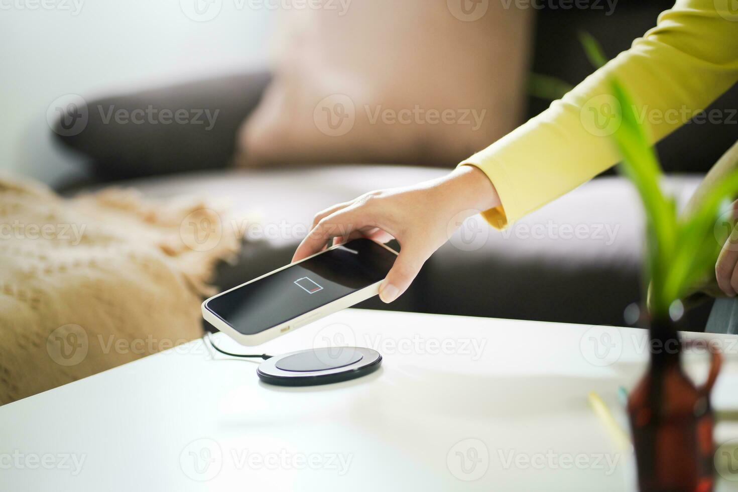 Charging mobile phone battery with wireless charging device in the table. Smartphone charging on a charging pad. Mobile phone near wireless charger Modern lifestyle technology concept. photo