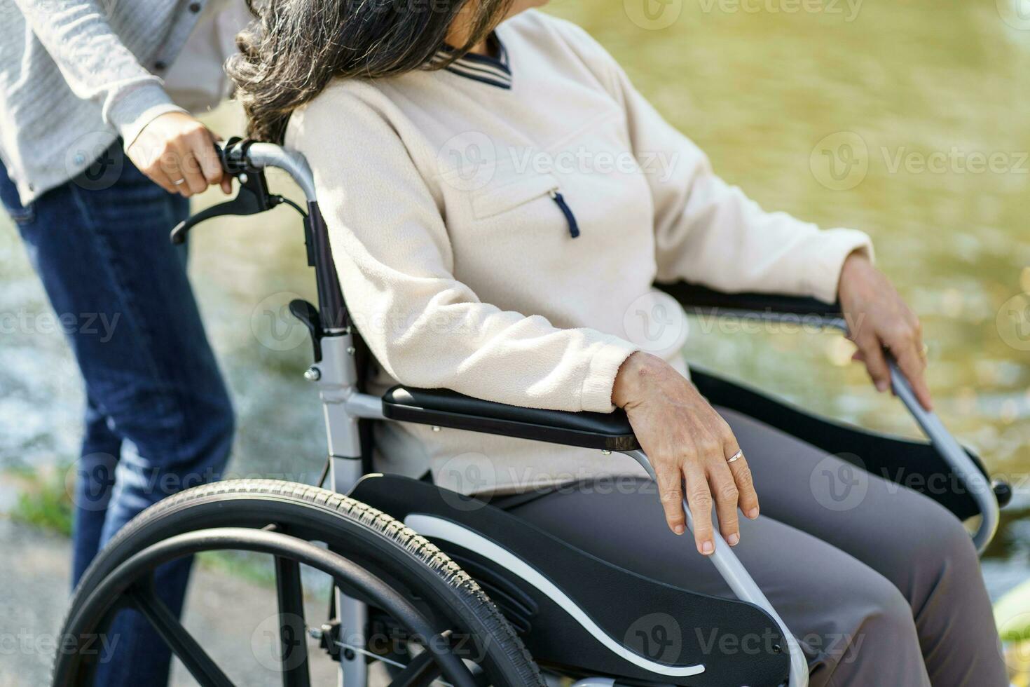 Nursing home. Young caregiver helping senior woman in wheelchair. photo