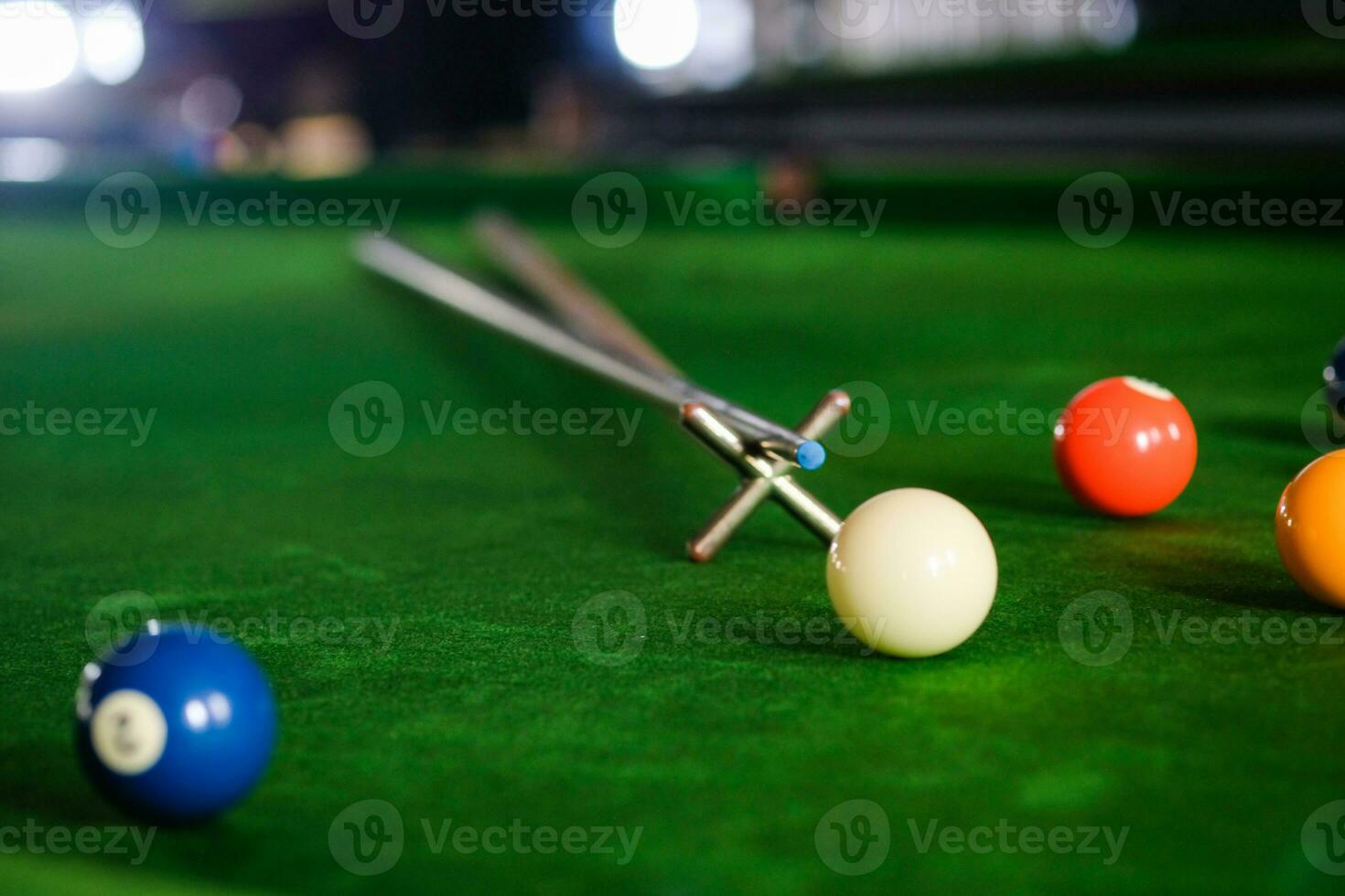 Man's hand and Cue arm playing snooker game or preparing aiming to shoot pool balls on a green billiard table. Colorful snooker balls on green frieze. photo