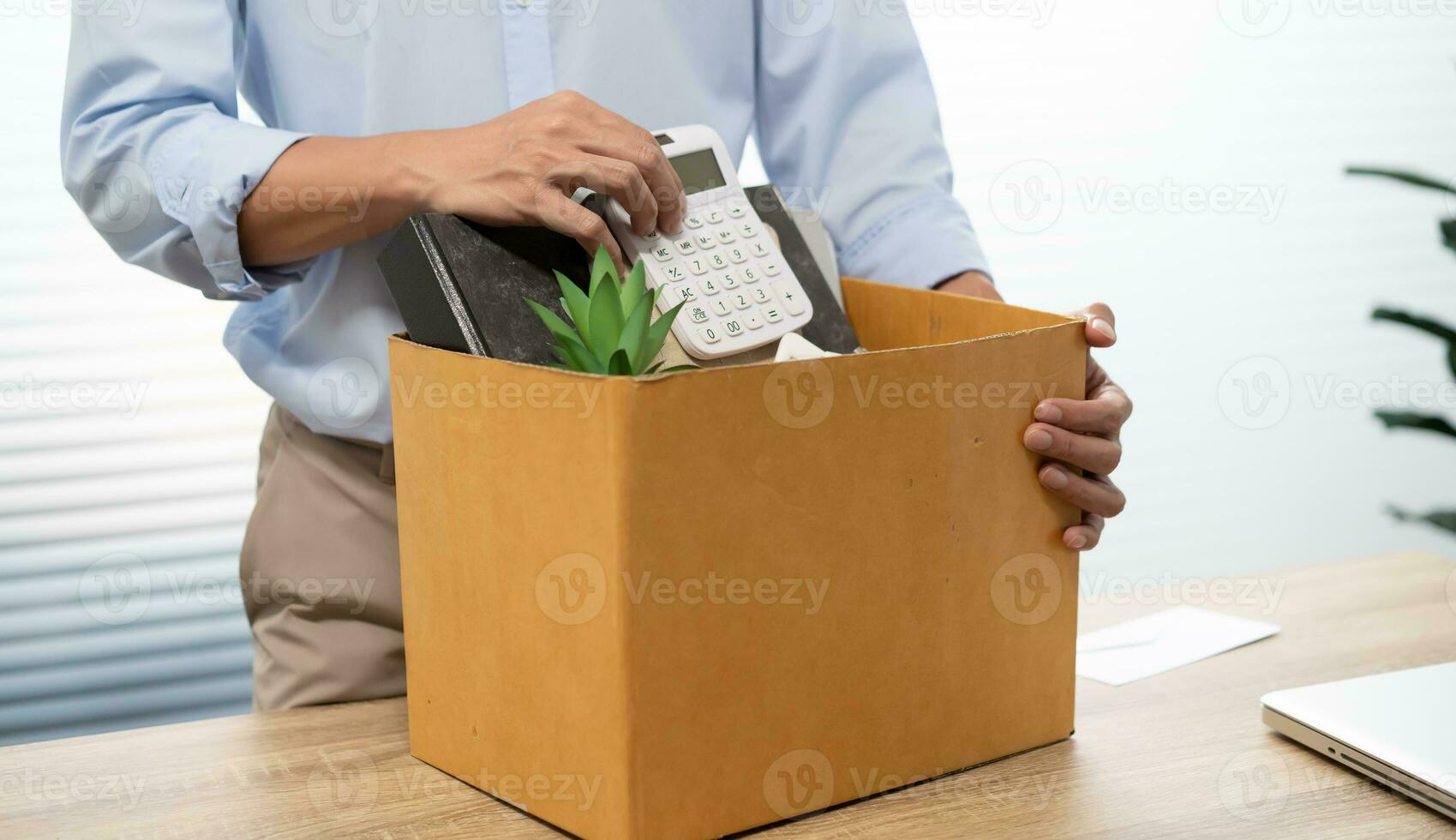 Business man sending resignation letter and packing Stuff Resign Depress or carrying business cardboard box by desk in office. Change of job or fired from company photo