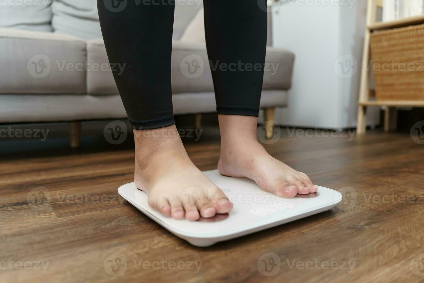 Fat diet and scale feet standing on electronic scales for weight control. Measurement instrument in kilogram for a diet control. photo