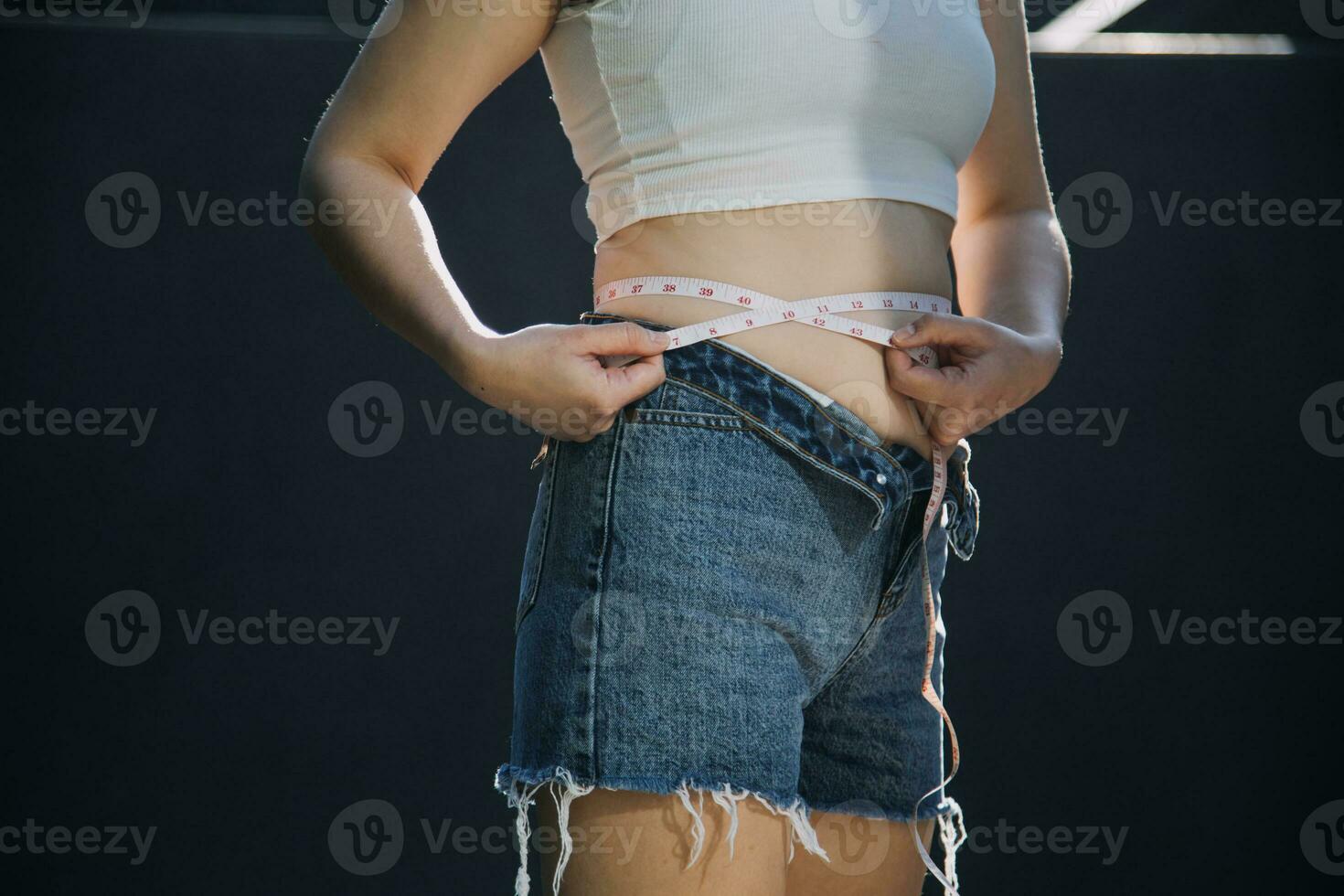 mujer gorda, barriga gorda, gordita, mujer obesa mano sosteniendo grasa abdominal excesiva con cinta métrica, concepto de estilo de vida de dieta de mujer foto