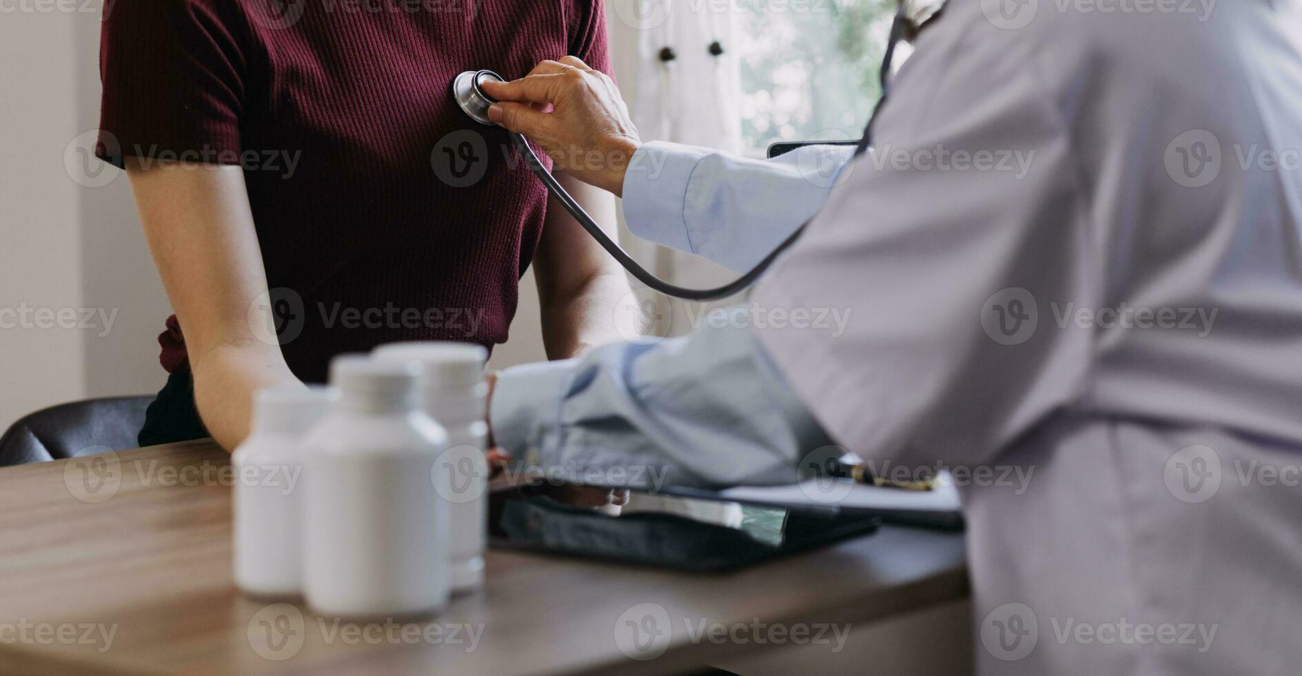 Homecare nursing service and elderly people cardiology healthcare. Close up of young hispanic female doctor nurse check mature caucasian man patient heartbeat using stethoscope during visit photo