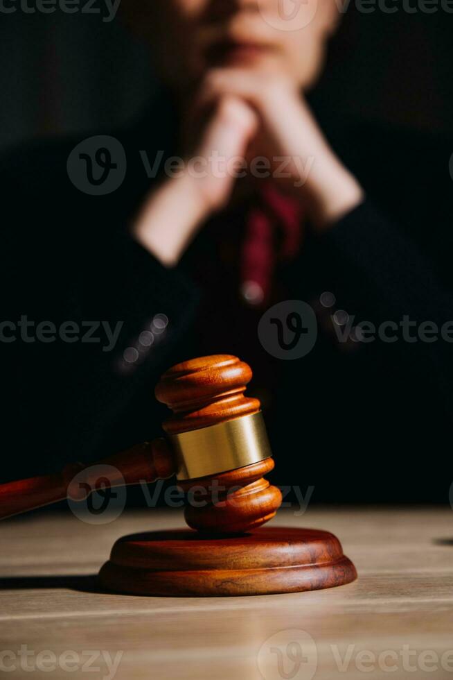 Justice and law concept.Male judge in a courtroom with the gavel, working with, computer and docking keyboard, eyeglasses, on table in morning light photo