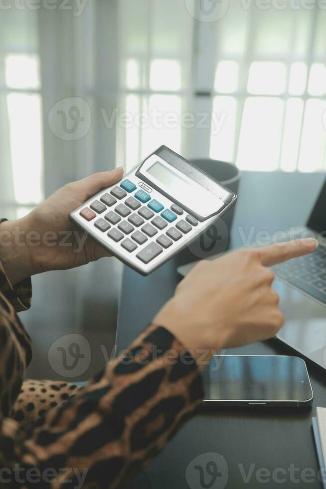 Portrait of Young Asian woman hand freelancer is working her job on computer tablet in modern office. Doing accounting analysis report real estate investment data, Financial and tax systems concept. photo