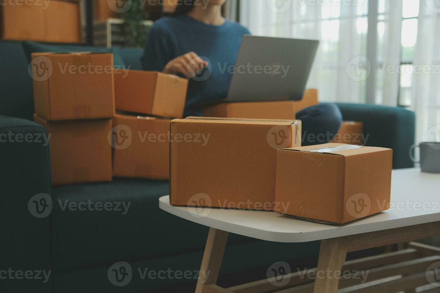 Startup small business entrepreneur or freelance Asian woman using a laptop with box, Young success Asian woman with her hand lift up, online marketing packaging box and delivery, SME concept. photo