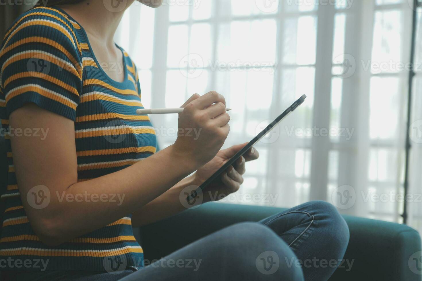 Young adult happy smiling Hispanic Asian student wearing headphones talking on online chat meeting using laptop in university campus or at virtual office. College female student learning remotely. photo