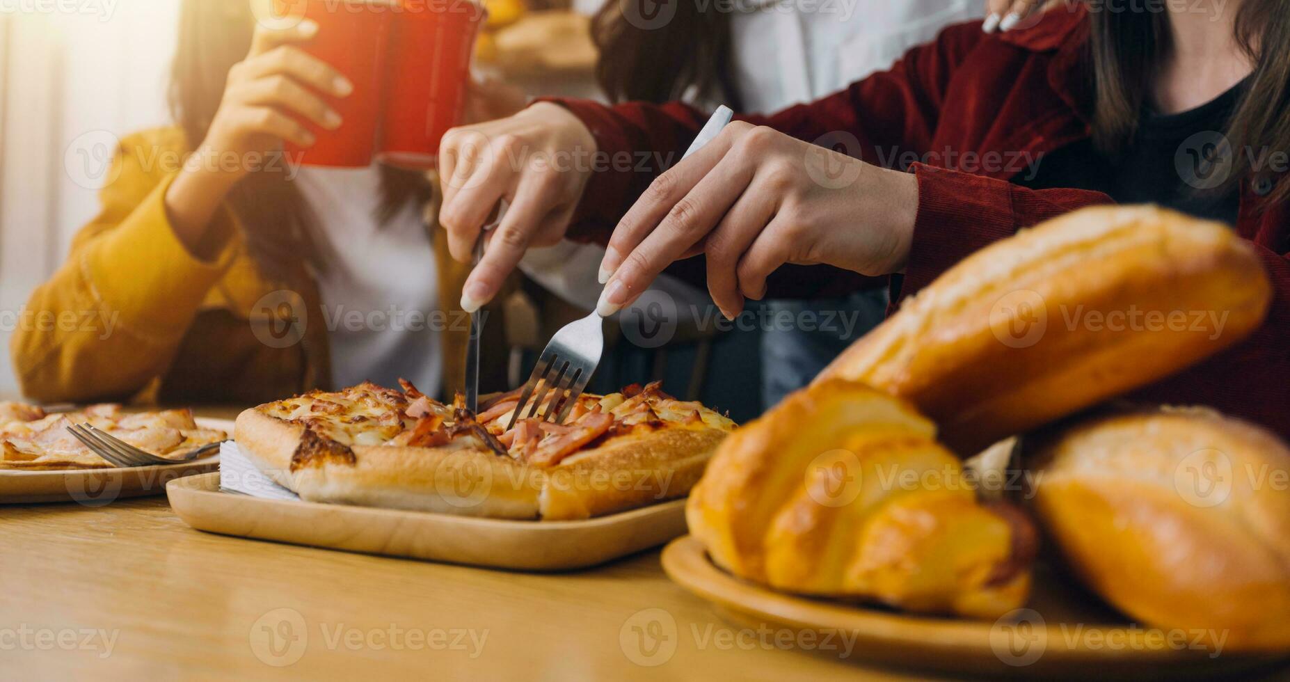 Laughing group of diverse young woman hanging out at home together and eating pizza photo