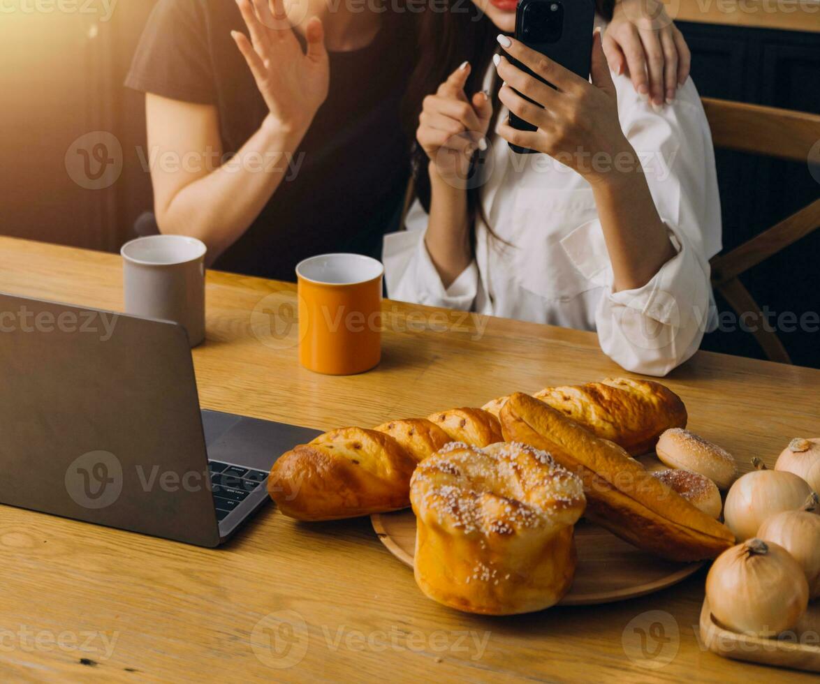 Happy two young women looking laptop computer during cooking together in kitchen room at home. Two young diverse lesbian women spending time together. LGBT and gender identity concept photo