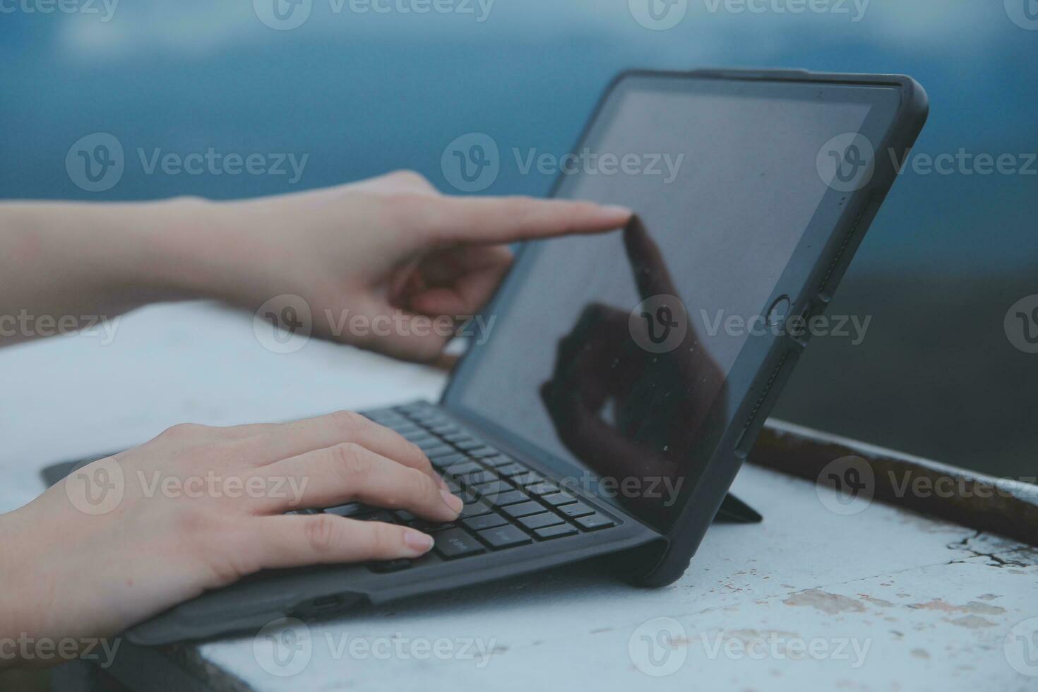 Young business woman working at the computer in cafe on the rock. Young girl downshifter working at a laptop at sunset or sunrise on the top of the mountain to the sea, working day. photo