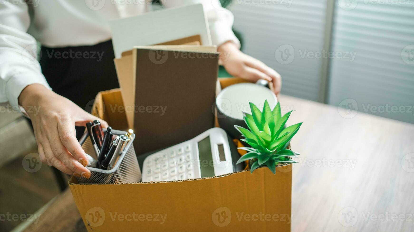 Business woman sending resignation letter and packing Stuff Resign Depress or carrying business cardboard box by desk in office. Change of job or fired from company photo