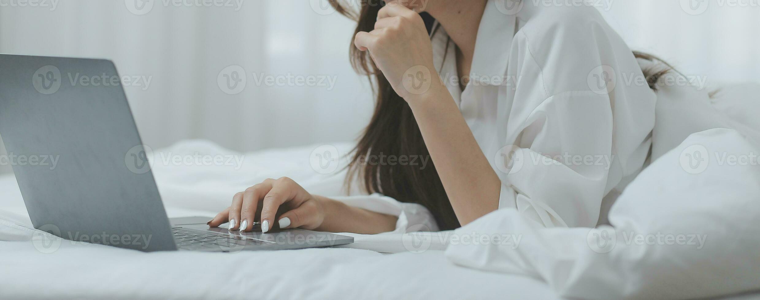 Happy freelance asian woman work on tablet on the hotel bed on travel trip. photo