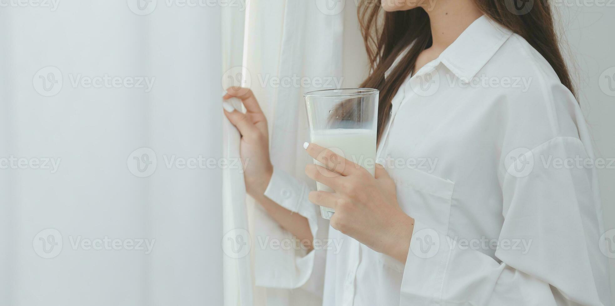 Happy young female in casual clothes smiling and looking at camera while using laptop on bed in bedroom at home photo
