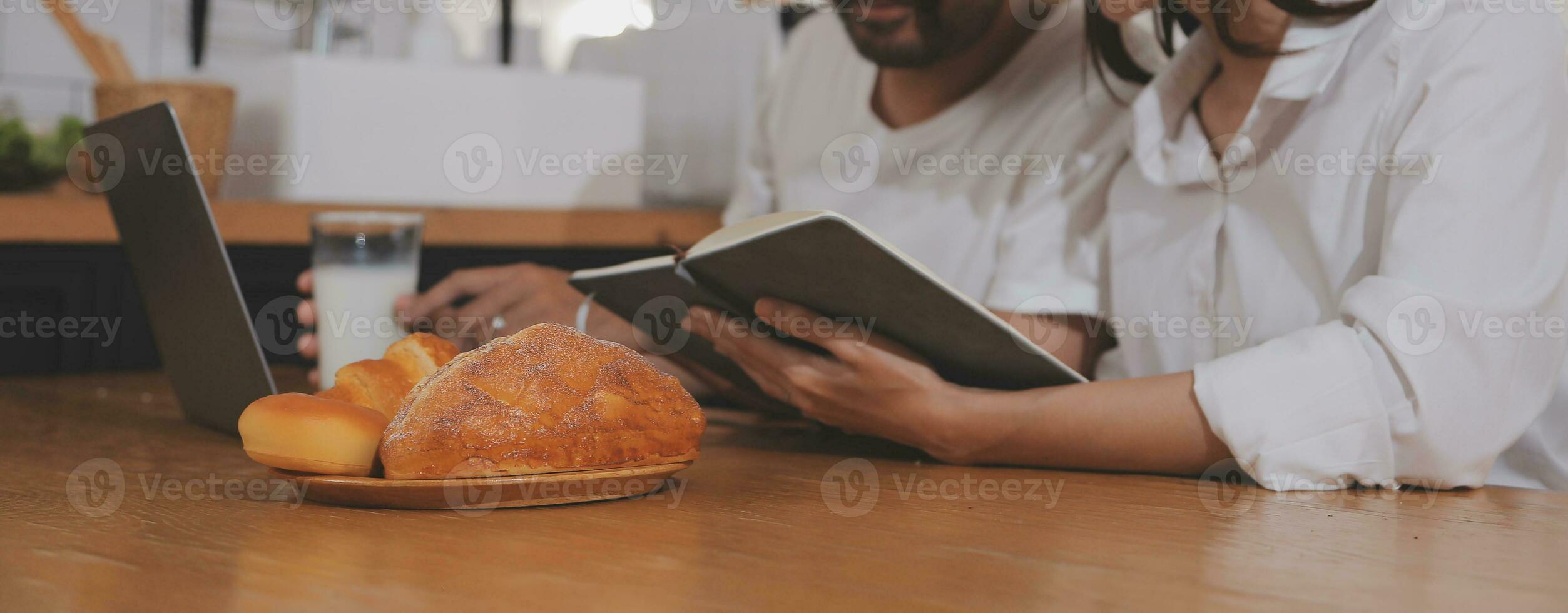 Handsome man sitting near his wife at kitchen. Family couple see social media, surf the web while sitting at kitchen table with generic laptop. Couple working with laptop at home photo